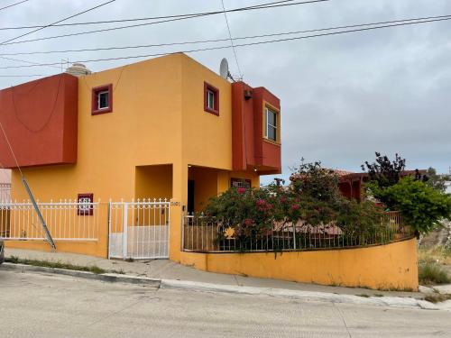 a yellow house with a fence and flowers at Terraza de campo in Rosarito