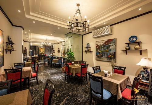 a restaurant with tables and chairs and a chandelier at Amanaki Saigon Boutique Hotel in Ho Chi Minh City