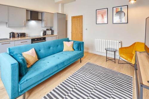 a living room with a blue couch and a kitchen at Host & Stay - North Marine House in Scarborough