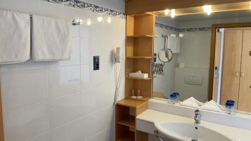 Baño blanco con lavabo y espejo en Tresa Bay Hotel, en Ponte Tresa