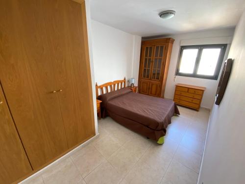 a small bedroom with a bed and a window at Apartamentos Sotavento Altamar in Alcossebre