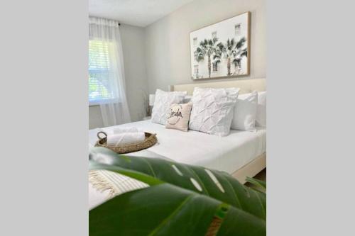 a bedroom with a bed with white sheets and pillows at Serenity at Seascape: Steps to the beach & Shops in Palm Beach Shores