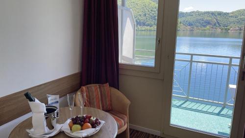 a room with a table with a bowl of fruit and a window at Tresa Bay Hotel in Ponte Tresa