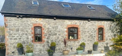 a stone building with windows and plants in front of it at The Old Stables in Swansea