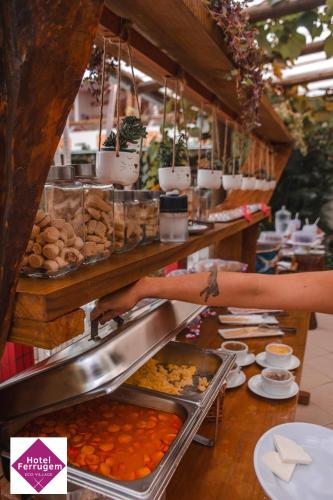 a person preparing food at a buffet in a restaurant at Hotel Ferrugem Eco Village in Garopaba
