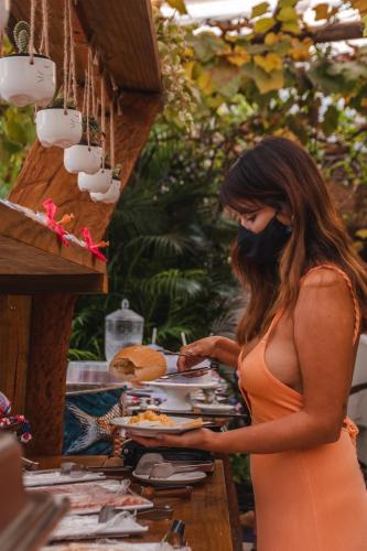 a woman in an orange dress preparing food at a buffet at Hotel Ferrugem Eco Village in Garopaba