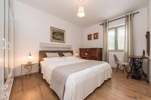 a white bedroom with a large bed and a desk at Villa Calendula in Novigrad Dalmatia