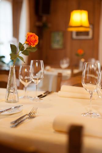 a table with wine glasses and a flower in a vase at Hotel Landgasthof Hirschen in Ramsen
