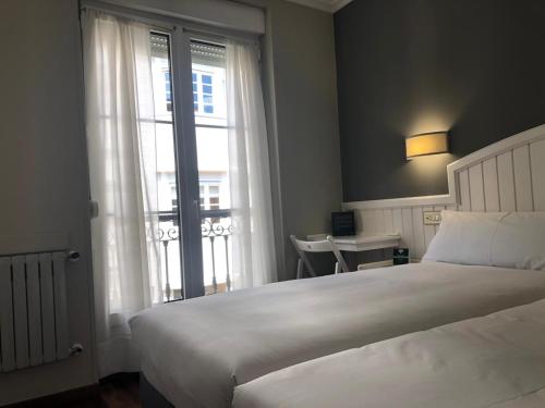 Un dormitorio con una gran cama blanca y una ventana en Alda Miramar Rooms en Gijón