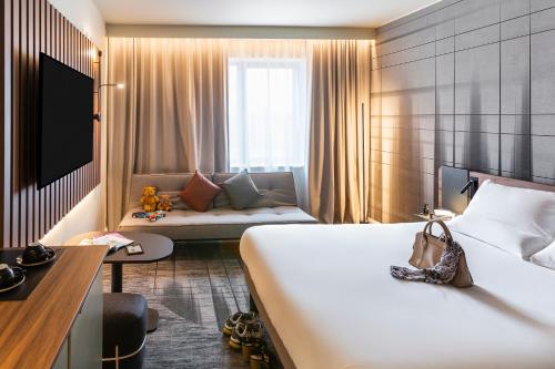 a hotel room with a bed and a couch at Novotel Cambridge North in Cambridge