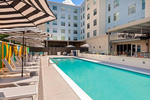 a swimming pool with lounge chairs and umbrellas at a hotel at Hyatt House Tampa Airport/Westshore in Tampa