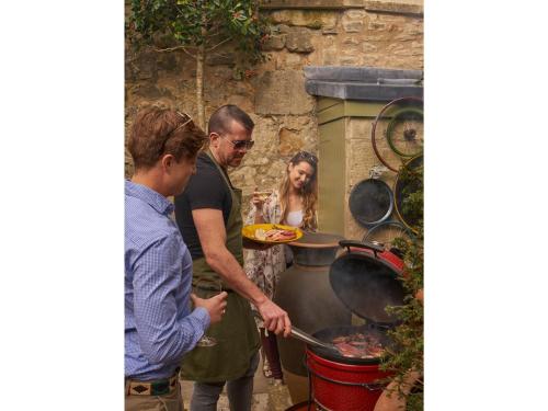 a group of people standing around a grill at Oppulent Lansdown Crescent Mews House with Free parking - Pass the Keys in Bath