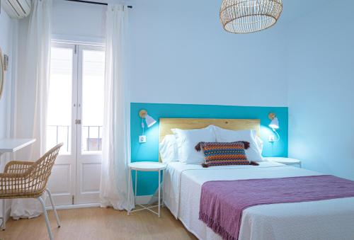 a blue bedroom with a bed and a chair at Hostal La Calzada in Tarifa