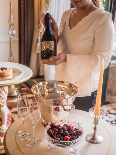 a woman holding a bottle of wine next to a table with wine glasses at EGO' Boutique Hotel - The Silk Road in Venice