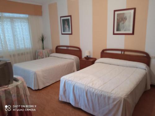 a hotel room with two beds and a tv at Pension Catro Ventos in Camariñas