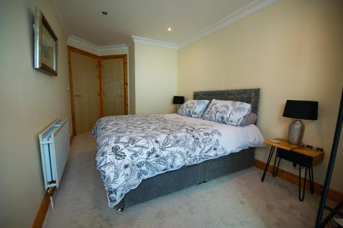 a bedroom with a bed and a table with a lamp at Seventeen Carrig Na Rone in Portrush