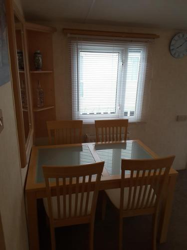 a dining room with a table and chairs and a clock at Annandale skegness in Skegness
