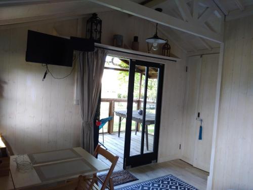 a room with a door to a porch with a television at Les Lodges de Phanou in Prissac