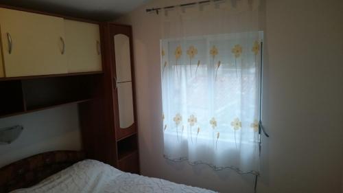 ein Schlafzimmer mit einem Bett und einem Vorhang an einem Fenster in der Unterkunft Holiday house near the see in Luka