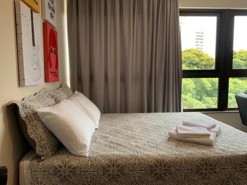Schlafzimmer mit einem Bett mit einem Kissen und einem Fenster in der Unterkunft Studio Central Belga Master Collection in Passo Fundo