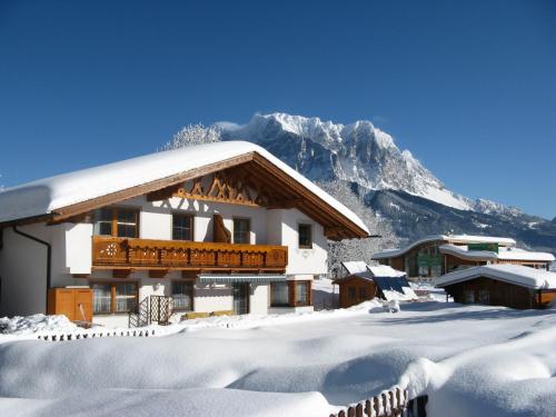 a snow covered building with a mountain in the background at Appartements Schneezauber in Lermoos