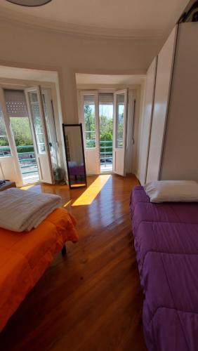 two beds in a room with wood floors and windows at Green View Home in Lisbon