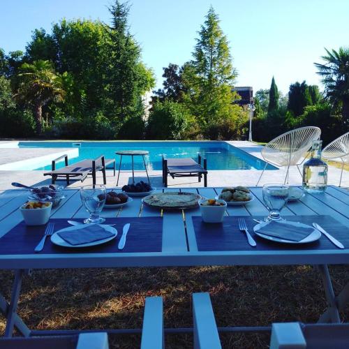 a blue table with plates of food next to a swimming pool at Bastide De Luzert in Labastide-de-Lévis