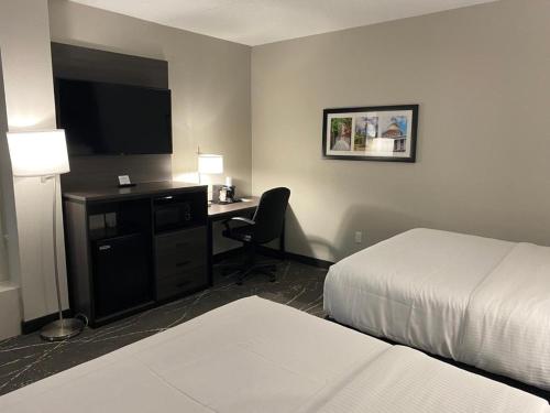 a hotel room with a bed and a desk with a television at Comfort Inn Boston Milford in Milford