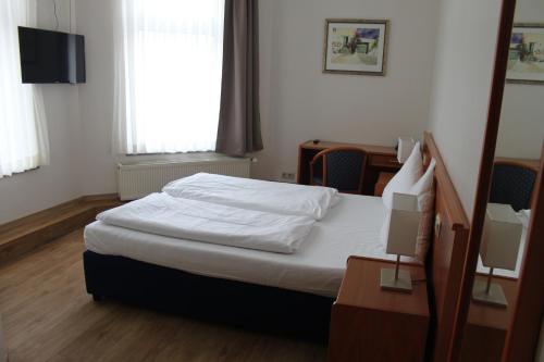 Schlafzimmer mit einem Bett, einem Schreibtisch und einem Fenster in der Unterkunft Stadt-Gut-Hotel Zum Rathaus in Oberhausen