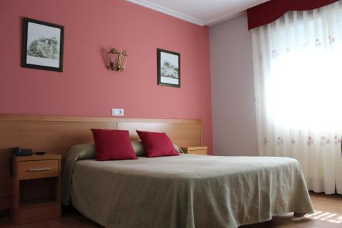 a bedroom with pink walls and a bed with red pillows at Hotel Rego Foz in Foz