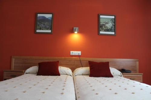 two beds in a bedroom with orange walls at Hotel Rego Foz in Foz