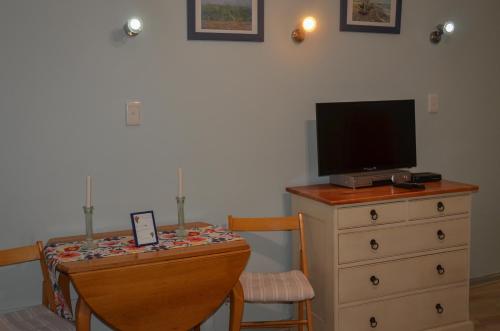 Habitación con mesa, TV y tocador. en Seaforth Beach Apartment, en Ciudad del Cabo
