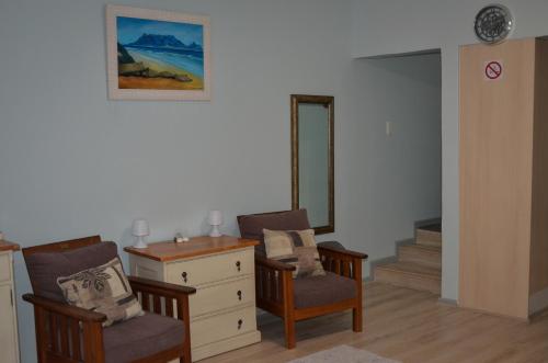 Habitación con 2 sillas, tocador y espejo. en Seaforth Beach Apartment, en Ciudad del Cabo