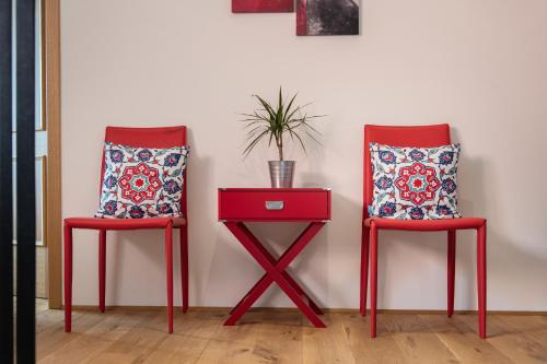 two red chairs and a red table with a plant at POSTHANSL in Gamlitz