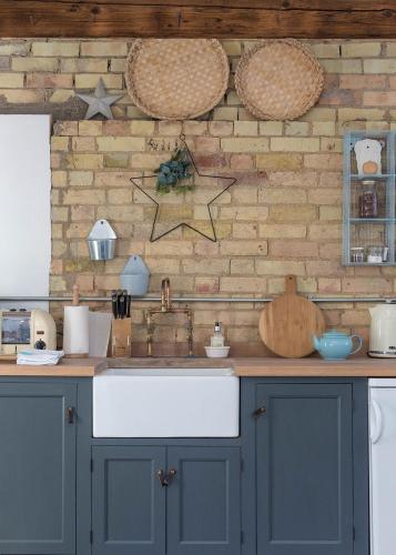 a kitchen with a white sink and a brick wall at Crafts Hill Barn in Cambridge