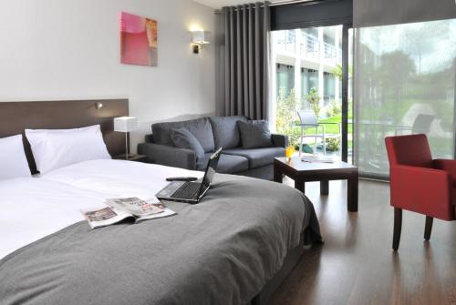 a hotel room with a bed with a laptop on it at Hotel Eden Park Pau Est, avec Piscine in Pau