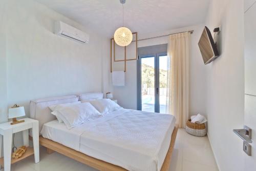バリにあるAsterios Villaの白いベッドルーム(ベッド1台、窓付)