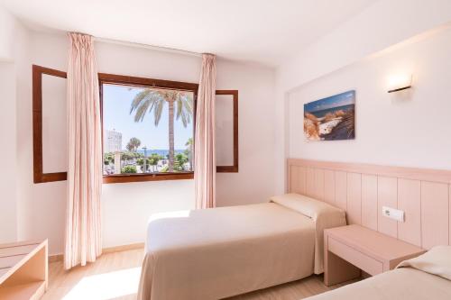 um quarto com 2 camas e uma janela em Apartamentos Vistamar I - MC Apartamentos Ibiza em Playa d'en Bossa
