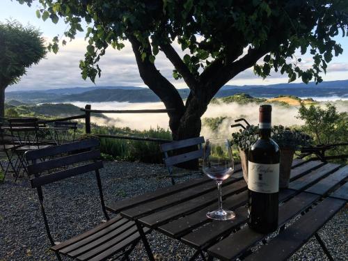 a bottle of wine and a glass on a picnic table at Cascina Bertolotto Wine Resort in Spigno Monferrato