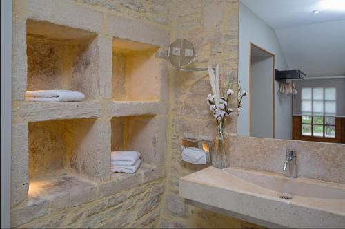 a stone bathroom with a sink and a mirror at Ferme de la Rançonnière - Hôtel & Restaurant in Crépon
