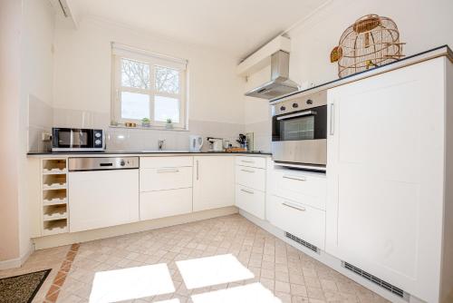 a white kitchen with white cabinets and a window at Bed & Breakfast Ohé en Laak in Ohé en Laak
