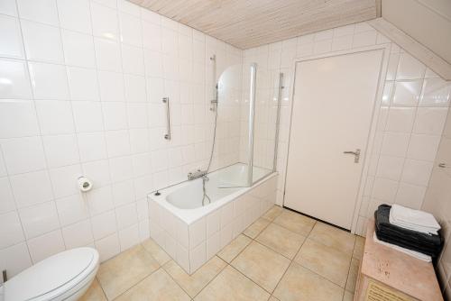 a white bathroom with a tub and a toilet at Bed & Breakfast Ohé en Laak in Ohé en Laak