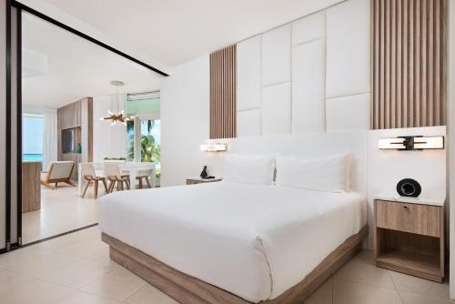 a bedroom with a large white bed and a dining room at Wymara Resort & Villas in Grace Bay