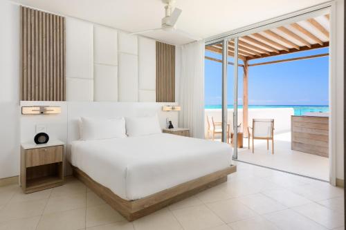 a bedroom with a white bed and a view of the ocean at Wymara Resort & Villas in Grace Bay