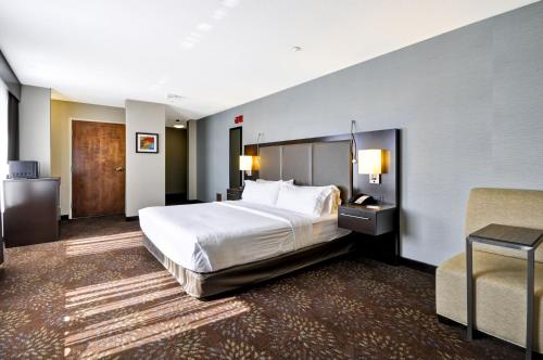 una habitación de hotel con una cama grande y una silla en Holiday Inn Express Romulus / Detroit Airport, an IHG Hotel, en Romulus