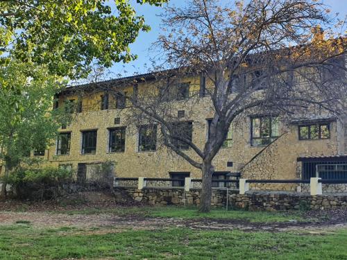 a large brick building with a tree in front of it at HOTEL MASIA EL MOLINETE in Mora de Rubielos