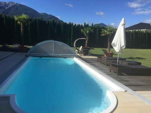 uma piscina azul com um guarda-chuva branco em VIII Panorama-Ferienwohnung Petzenblick em Sankt Michael ob Bleiburg