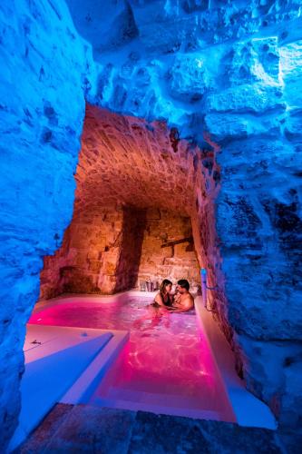 two people swimming in a hot tub in a cave at Petra Suite in Alberobello
