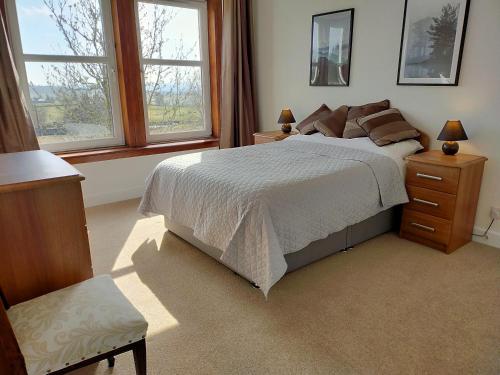 a bedroom with a large bed and two windows at Buckieburn - self-catering - rural in Stirling
