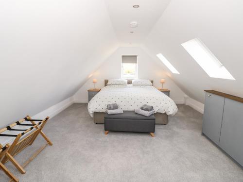 a white bedroom with a bed and a chair at Meadow Cottage in Broadway